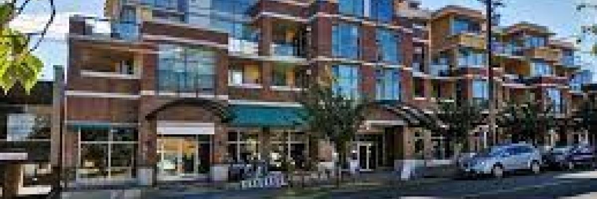 View from across the street of red brick condos, three stories high, with the sun behind so they are in the shade.