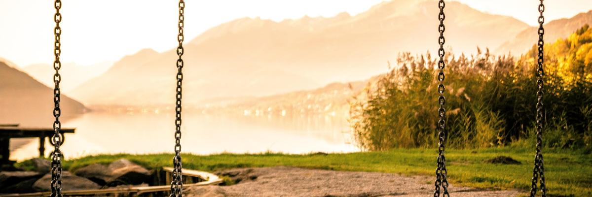 two swings in front of a mountain lake