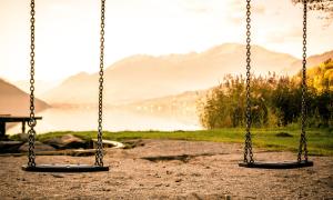 two playground swings in front of a mountain sunset backdrop