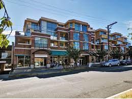 View from across the street of red brick condos, three stories high, with the sun behind so they are in the shade.